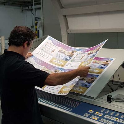 Bild vergrößern: Ein Fachmann für Druckmedien prüft eine Druckvorlage vor einem Spezialgerät.